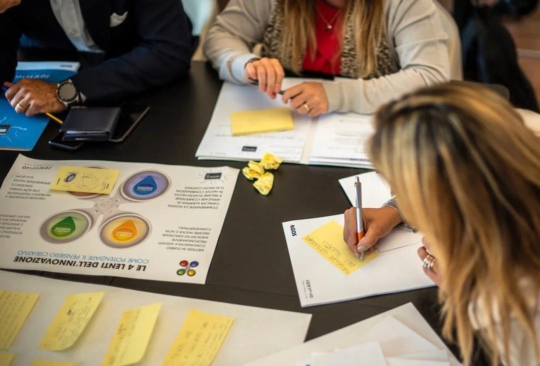 Overhead view of a workshop table covered in printed canvases, sticky notes and pens.
